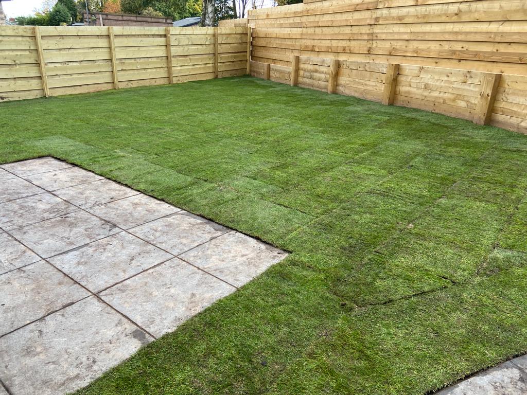 Freshly laid turf lawn completing a garden transformation next to a stone patio and wooden fence in Nottinghamshire.